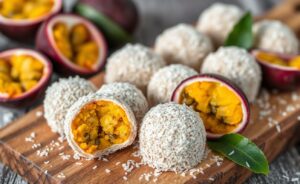 Trufas de Maracujá cobertas com coco ralado, dispostas em tábua de madeira com decoração de maracujá fresco